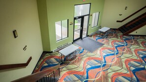 A hotel lobby with a colorful carpet, a staircase, and a table with chairs.