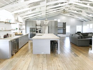 Una cocina amplia con una isla central, electrodomésticos modernos y un techo alto con vigas a la vista.