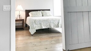 A bedroom with a bed, a nightstand, a lamp, and a sliding door.