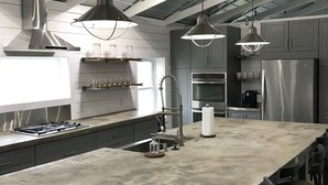 A modern kitchen with a large island, stainless steel appliances, and pendant lighting.