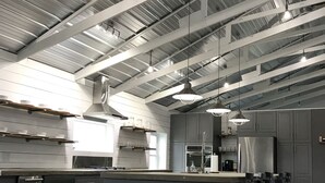 A modern kitchen with stainless steel appliances, a large island with bar stools, and a high ceiling with exposed beams.