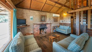 Un salon chaleureux avec une cheminée, un téléviseur et des fauteuils confortables.