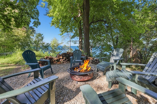 A fire pit surrounded by Adirondack chairs in a wooded area with a clear view of the sky. - 2027 NOW OPEN! LAKEFRONT HOME WITH PRIVATE HEATED POOL! (Lakeside)