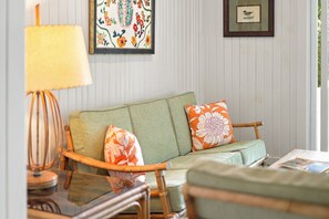 A room with a green sofa, a lamp, and two framed artworks on the wall. - 2027 NOW OPEN! LAKEFRONT HOME WITH PRIVATE HEATED POOL! (Lakeside)