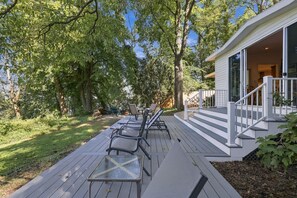 A deck with outdoor furniture, a glass table, and a covered porch area.