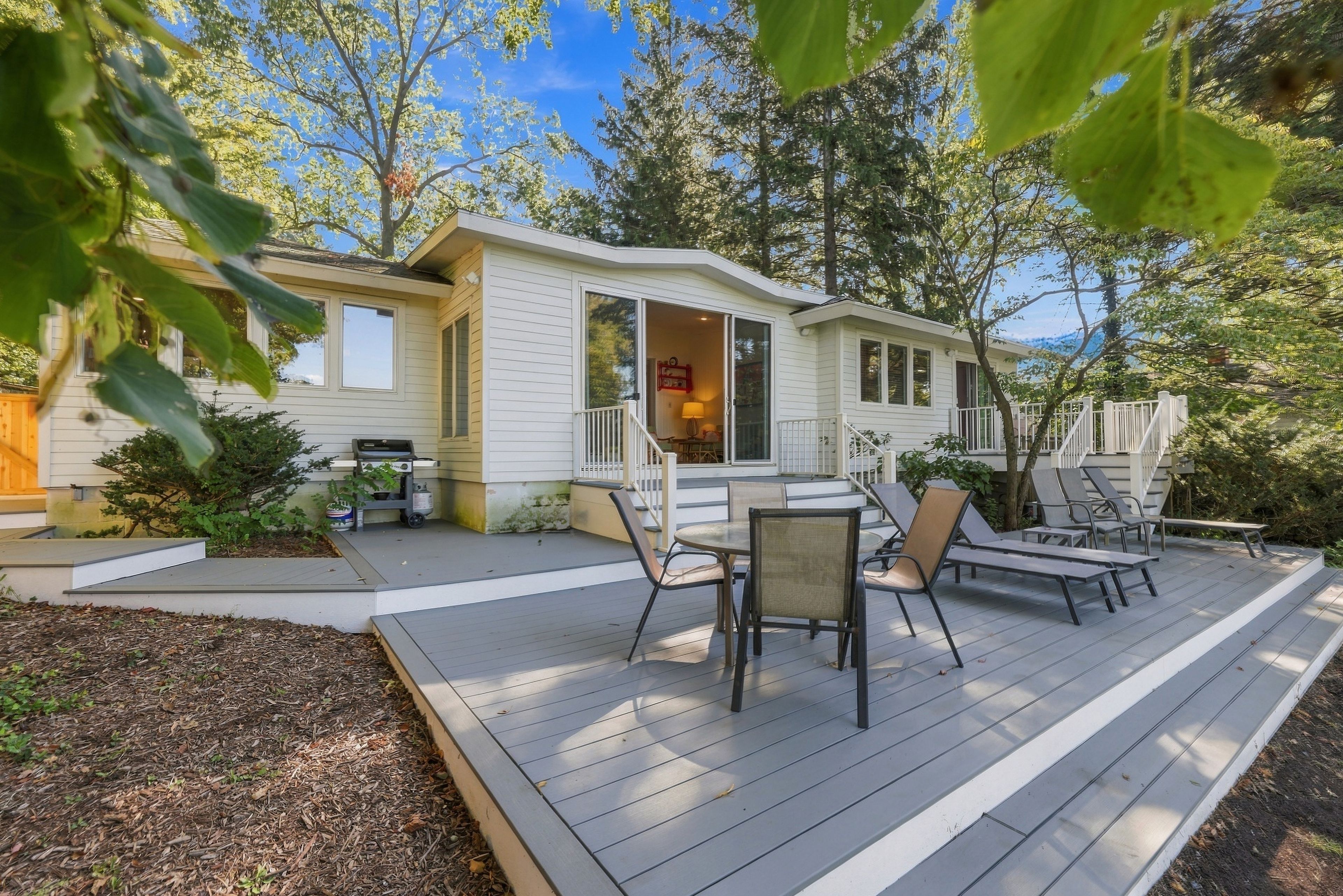 Une maison à deux étages dotée d’un patio couvert aménagé avec du mobilier d’extérieur.