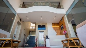 A spacious lobby with a curved staircase, a reception desk, and a chandelier.