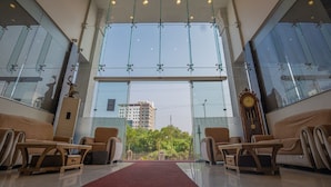 A spacious lobby with large glass windows, a chandelier, and a clock on the wall.