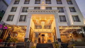 A hotel with a white facade, a central entrance with a chandelier, and a sign reading "V-Star".