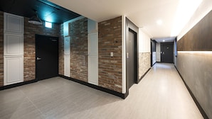 A modern hallway with brick walls, white panel doors, and a tiled floor. - Busan No.25 Yongho (Busan)