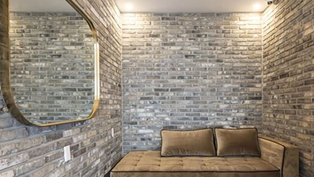A room with a brick wall, a round mirror, a brown sofa, and two white tables. - Busan No.25 Yongho (Busan)