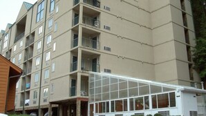 A multi-story hotel with balconies, a glass entrance, and a parking area. -  In Town with a Spectacular View - Walk to the Parkway! (Gatlinburg)