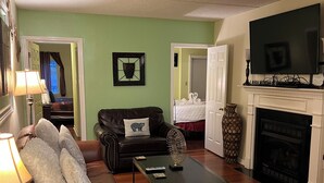 A living room with a sofa, coffee table, fireplace, television, and a door leading to another room. -  In Town with a Spectacular View - Walk to the Parkway! (Gatlinburg)