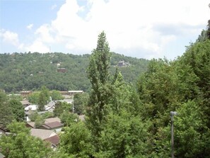 A residential area with houses surrounded by dense greenery and hills in the background.
