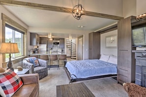 A bedroom with a bed, a sofa, a TV, and a dining area.