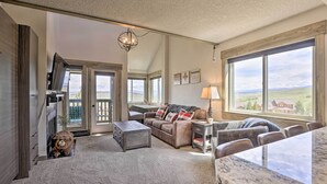 A spacious living room with a large window, a cozy fireplace, and a comfortable seating area.