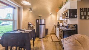 Une cuisine compacte équipée d’un réfrigérateur, d’une cuisinière, d’un four à micro-ondes et d’un coin repas avec une table et des chaises.