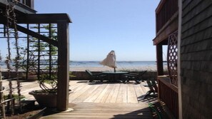 Une terrasse en bois avec une table et des chaises, donnant sur une plage.