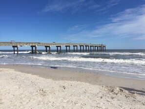 A beach with a pier extending into the ocean.