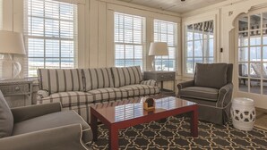 A living room with a striped sofa, a grey armchair, a wooden coffee table, and a patterned rug.