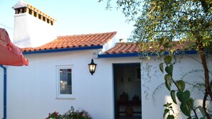 Un edificio blanco con techo de tejas, una ventana pequeña y una puerta.