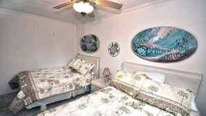 A bedroom with two single beds, a ceiling fan, and decorative wall art. - Pretty, spacious 2-bedroom condo with free WiFi and adorable coastal decor located uptown and only a half a block from the beach! (Ocean City)