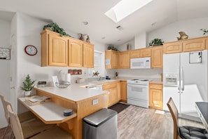 A modern kitchen with wooden cabinets, a white countertop, a built-in oven, a microwave, and a refrigerator.