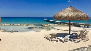 Ein Strand mit Liegestühlen und einem Strohdachschirm.