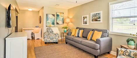 A living room with a gray sofa, patterned rug, and a ceiling fan.