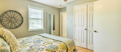 Une chambre à coucher avec un lit, un ventilateur de plafond, une fenêtre et une porte.