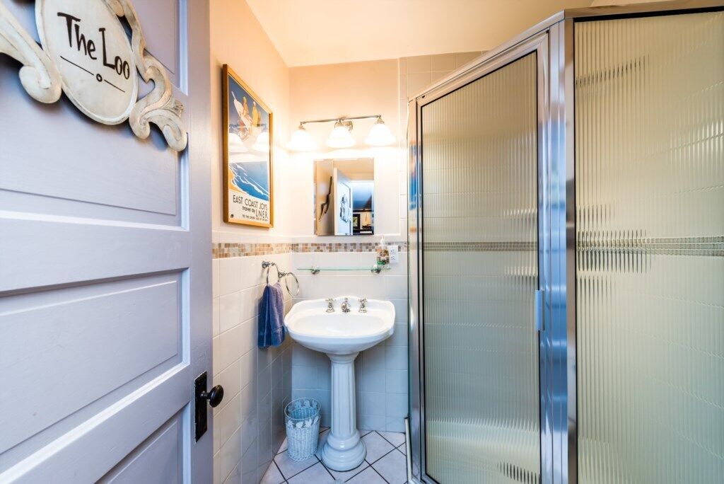 A bathroom with a white sink, a glass shower enclosure, a towel rack, and a mirror.