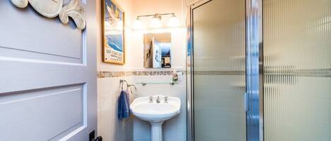 A bathroom with a white sink, a glass shower enclosure, a towel rack, and a mirror.