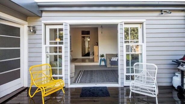 A covered porch with two chairs, a rug, and a door leading to an interior space. - Yellow Door Coburg | Boutique Accommodation | Sleeps up to 16 guests (Coburg)