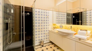 A modern bathroom with a glass-enclosed shower, a white sink, and a large mirror. - Original Studio in Bolhão Market (Oporto)