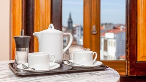 A breakfast setup with a coffee maker, teapot, cups, and saucers on a tray, with a city view through a wooden door. - Original Studio in Bolhão Market (Oporto)
