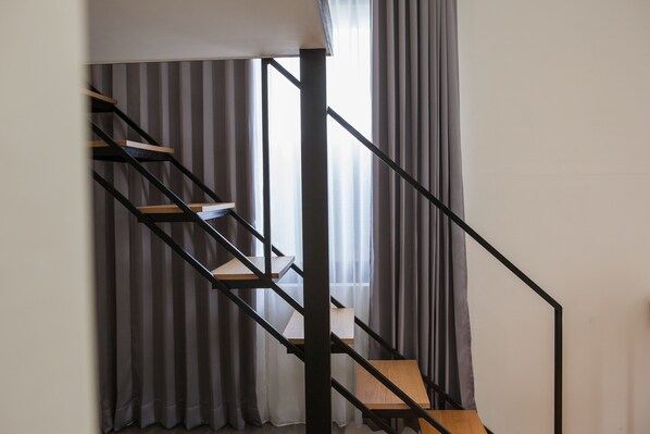 A staircase with wooden steps and black metal railings, leading to a landing with a white ceiling. - Rainbow Hotel (Magong)