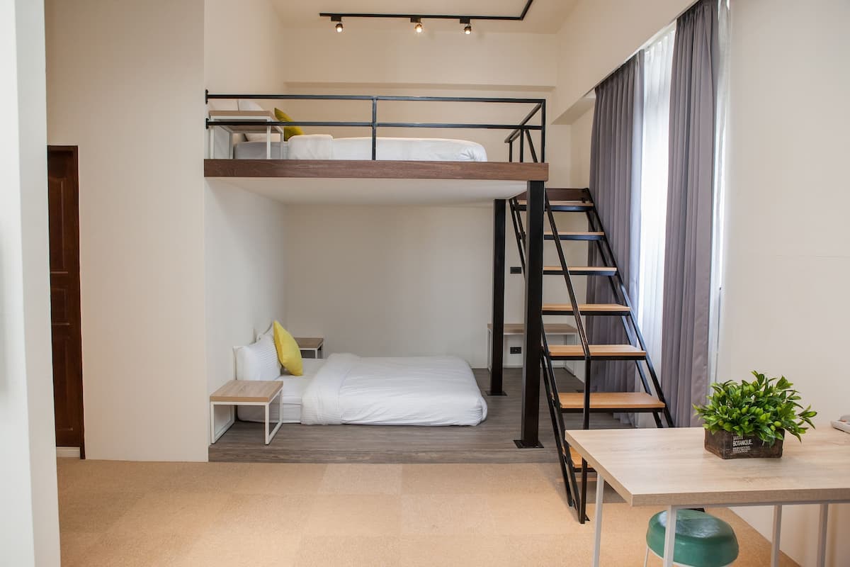 A compact room with a bunk bed, a desk, a chair, and a staircase.
