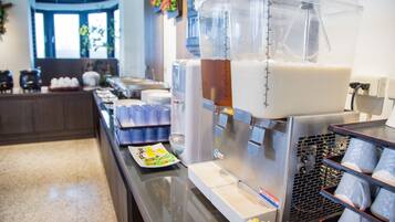 A buffet area with a beverage station, serving trays, and a window with natural light.