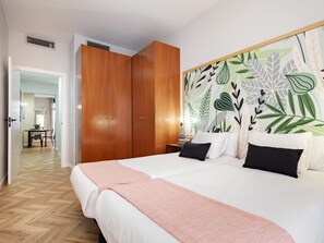 A bedroom with a large bed, wooden wardrobe, and a wall with a leaf pattern. - ART HOUSE SAGRADA FAMILIA 1 (BARCELONA)
