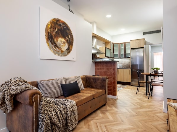 A modern living room with a brown leather sofa, a leopard print throw, and a large abstract painting on the wall. - ART HOUSE SAGRADA FAMILIA 1 (BARCELONA)