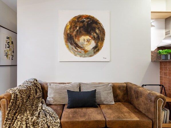 A brown leather sofa with striped cushions and a leopard print throw blanket.