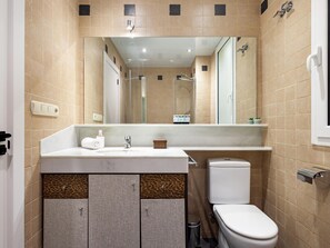 A bathroom with beige tiles, a white sink, a mirror, a toilet, and a shower. - ART HOUSE SAGRADA FAMILIA 1 (BARCELONA)