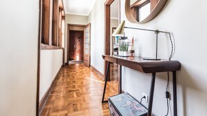 Un couloir avec un plancher en bois, un bureau avec une lampe et un miroir accroché au mur.