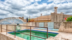 Una piscina en la azotea con vistas al paisaje urbano, un amplio ventanal de arco y una pequeña estatua de un búho.