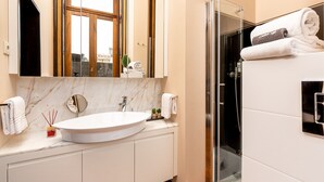 Een moderne badkamer met een grote spiegel, een witte wastafel en een douche met glazen wanden.