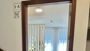 A staircase leading to a room with a bed, a window with curtains, and a door with a sign indicating '1-A Apartment.' - Well Decorated Studio in Santa Catarina Street (Oporto)
