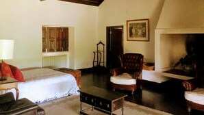 Una habitació amb llit, una cadira, una taula, una xemeneia i una porta.