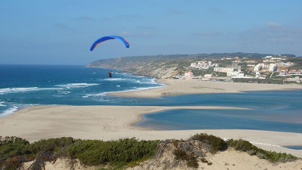 Vistes costaneres amb una platja, l'oceà i un poble al fons.