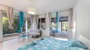Een slaapkamer met een bed, een stoel, een tafel en grote ramen.