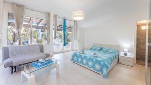 Een moderne slaapkamer met een bed, een bank, een glazen salontafel en een nachtkastje.